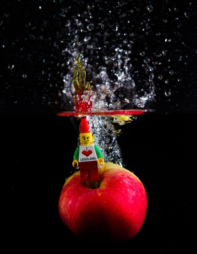LEGO mini figure riding an apple as it splashes into water