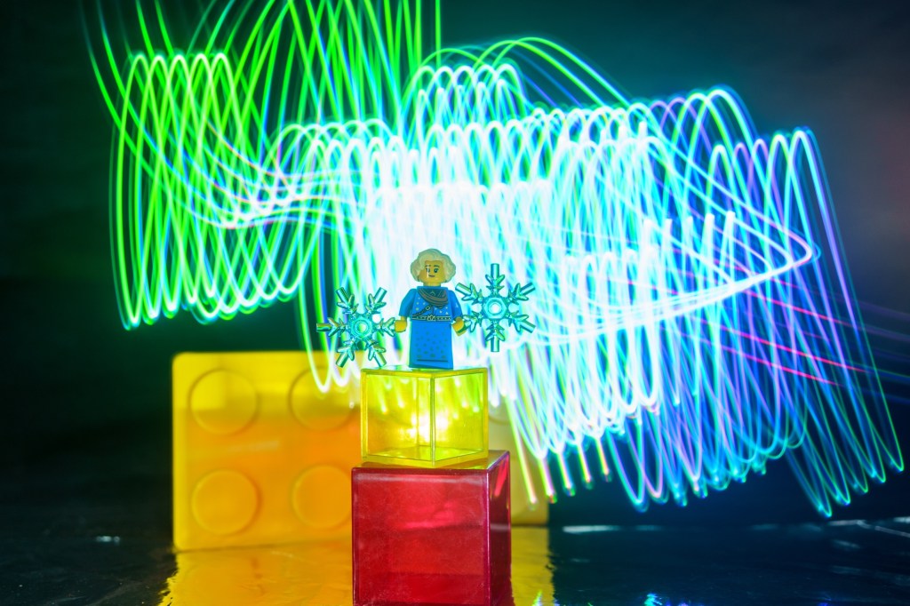 Lego figure with icicles for hands and light painting traces in the background
